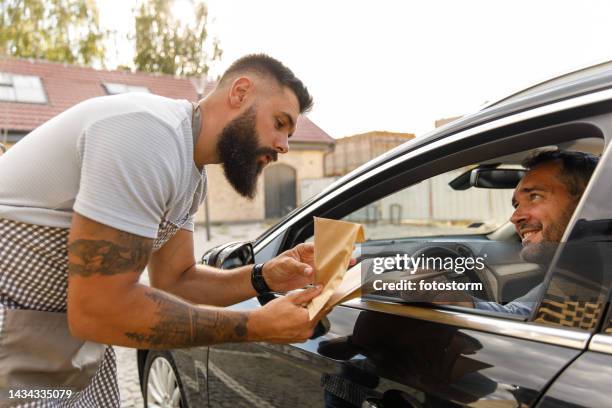 delivery man giving customer his curbside pickup orders - drive through stock pictures, royalty-free photos & images