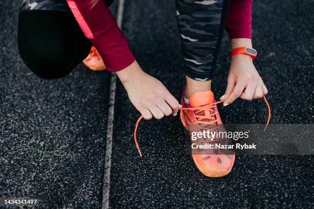 unrecognisable woman tying laces on sports shoes for running - tying stock pictures, royalty-free photos & images