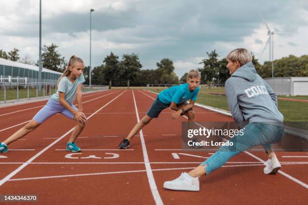 athletics mother running coach working with her children during a training session - kids track and field stock pictures, royalty-free photos & images