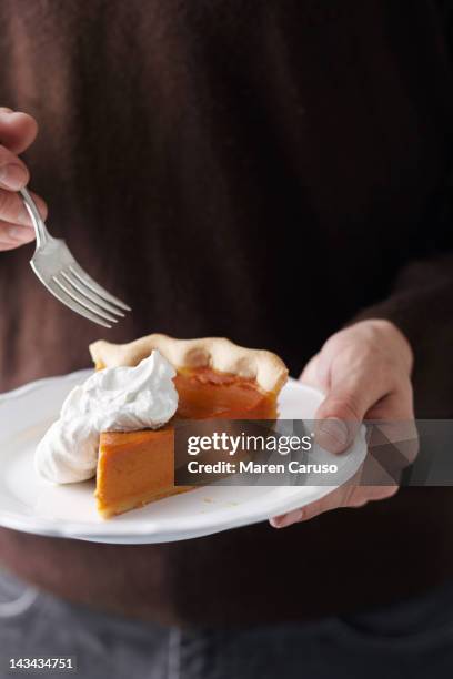 man holding plated pumpkin pie slice and fork - man eating pie stock-fotos und bilder