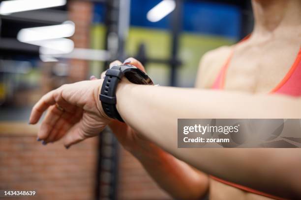 frau, die nach dem training im fitnessstudio auf ihre smartwatch schaut - fitness tracker stock-fotos und bilder