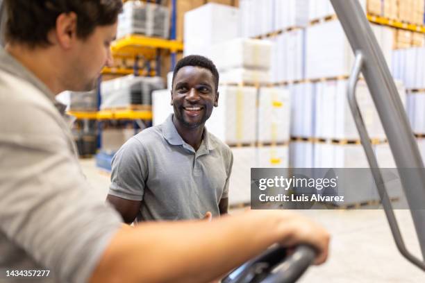 supervisor talking to forklift truck operator in a warehouse - warehouse worker stock-fotos und bilder