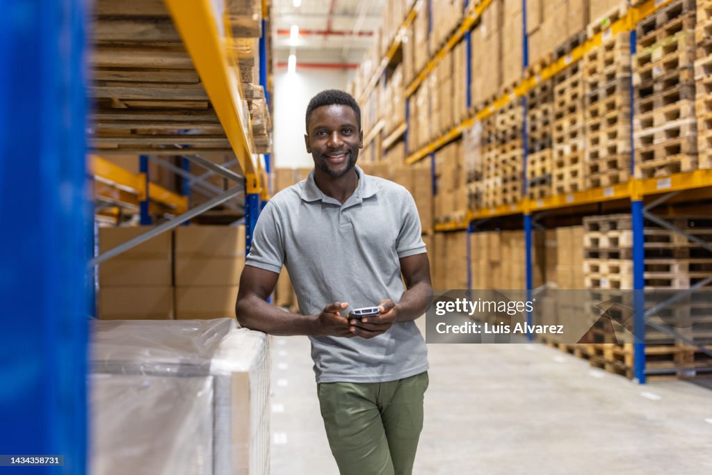 Portrait of a male warehouse worker standing by rack with scanner device