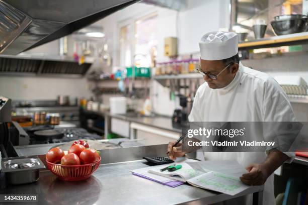 un chef calculando los gastos de cocina - indian economy business and finance fotografías e imágenes de stock