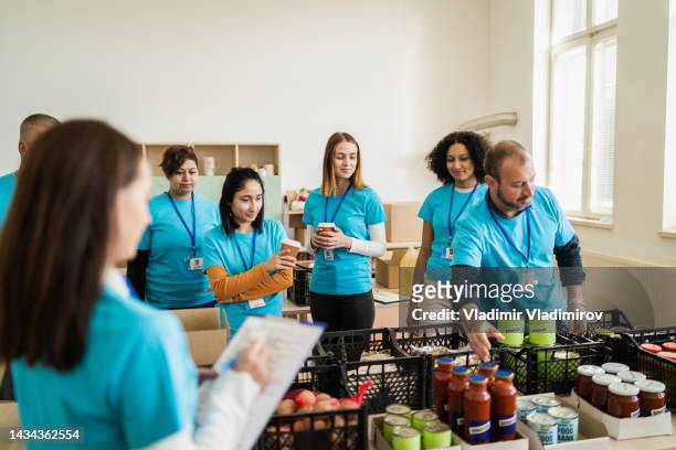 aid workers are standing near donated food supplies - clothing donations stock pictures, royalty-free photos & images