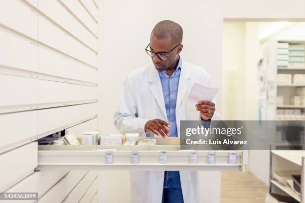 pharmacist looking for prescription medication in shelf at drugstore - apotheke rezept stock-fotos und bilder