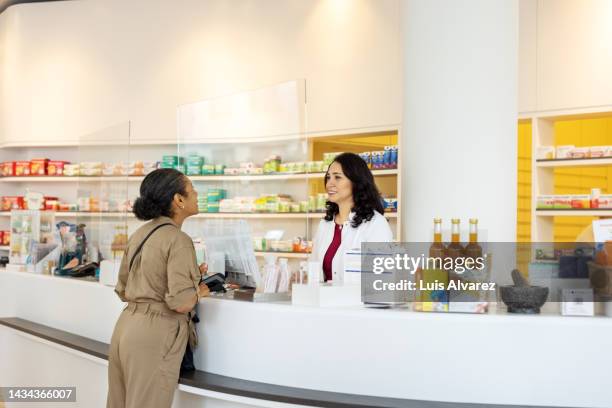 pharmacist assisting female customer at checkout counter - pharmacist and patient stock pictures, royalty-free photos & images