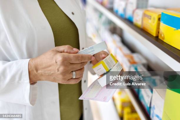 close up of woman pharmacist searching the medicines at storage shelf - prescription imagens e fotografias de stock