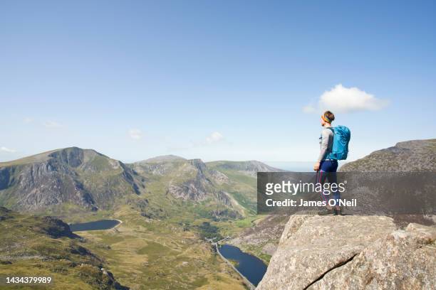 lone female looking out at rugged mountain landscape on sunny day - parque nacional de snowdonia imagens e fotografias de stock