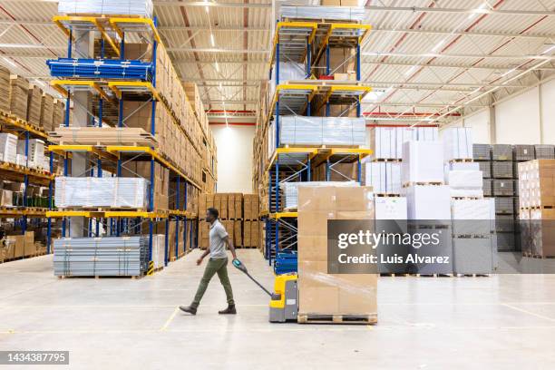 worker moving cargo in distribution warehouse - pallet jack stock pictures, royalty-free photos & images