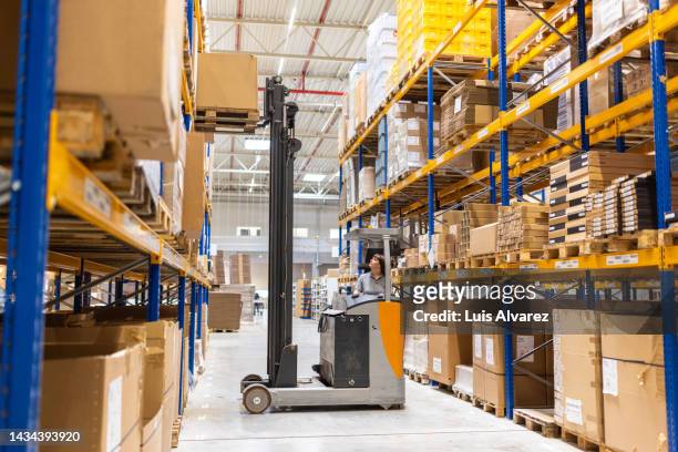 woman operating a forklift loader in a factory warehouse - pallet industrial equipment fotografías e imágenes de stock