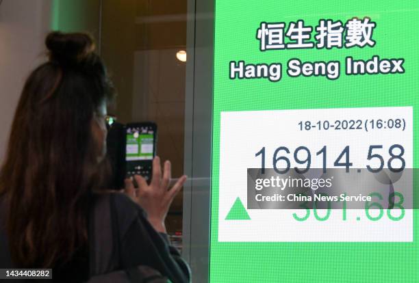 Woman takes photos of an electronic screen displaying the numbers for the Hang Seng Index on October 18, 2022 in Hong Kong, China.