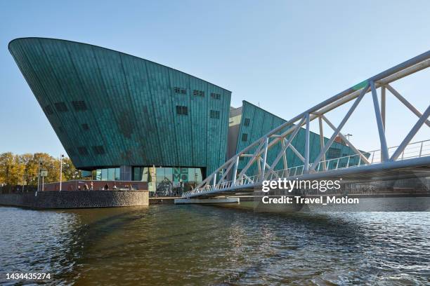 steel walking bridge at the nemo museum science center modern green building in amsterdam - science center stock pictures, royalty-free photos & images