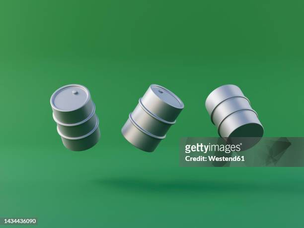 three dimensional render of oil drums floating against green background - oil barrels stock pictures, royalty-free photos & images