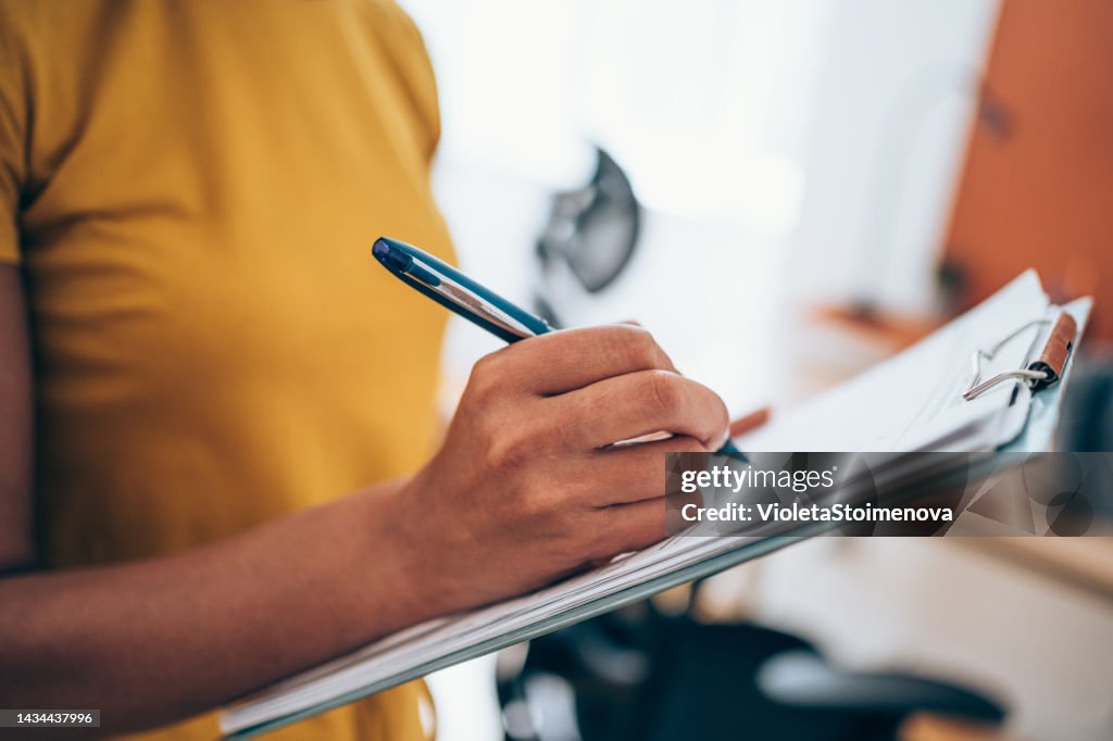 Woman hand writing on clipboard with a pen.