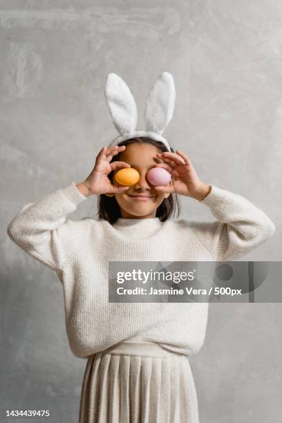 portrait of girl holding easter egg while standing against wall,nigeria - frühling deko stock-fotos und bilder