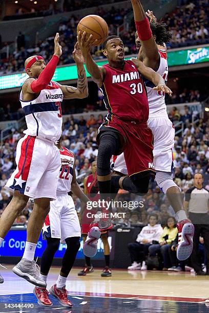 Miami Heat point guard Norris Cole drives to the basket between Washington Wizards power forward James Singleton , left and center Nene for two...