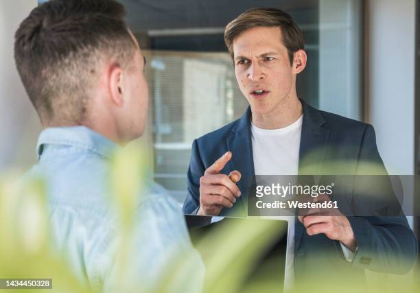 angry businessman arguing with colleague in office - ammonite foto e immagini stock