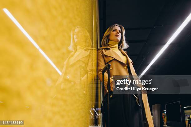 beautiful business woman with a suitcase  waiting for a train in the subway. - yellow suitcase stock pictures, royalty-free photos & images