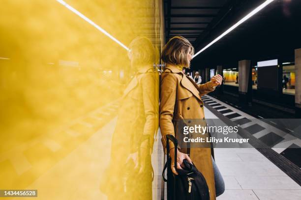 beautiful business woman with a suitcase  waiting for a train in the subway. - abwarten stock-fotos und bilder