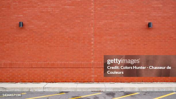 empty red brick wall with two lamps, cement sidewalk and asphalt street in montreal, qc, canada - red wall stockfoto's en -beelden