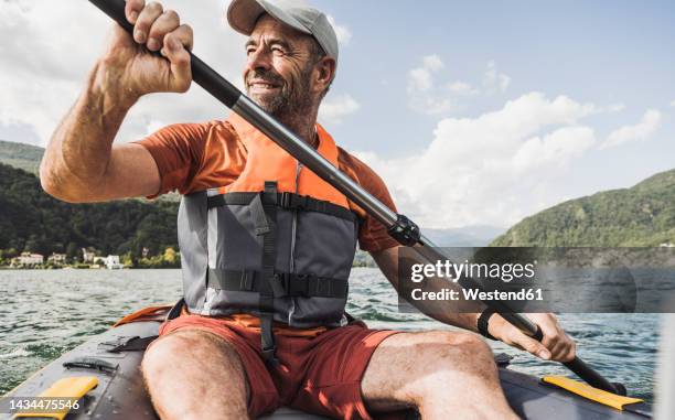 smiling mature man rowing kayak boat on sunny day - boat rowing stock pictures, royalty-free photos & images