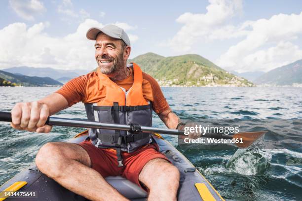 happy mature man enjoying rowing kayak boat on sunny day - kayak stock-fotos und bilder