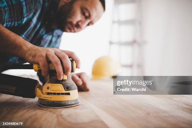 handwerker schleift einen holztisch. - schmirgelmaschine stock-fotos und bilder