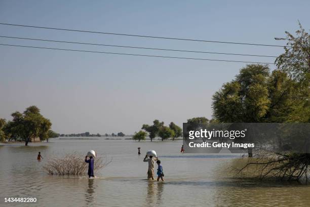 People walk through floodwater on October 18, 2022 in Johi, Pakistan. Nearly one-third of Pakistan was deeply affected by flooding which hit the...