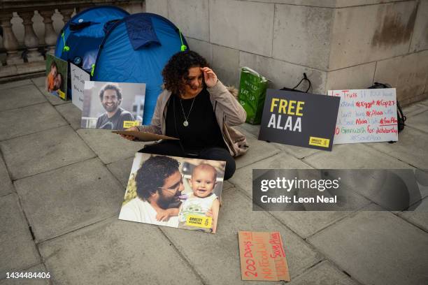 Mona Seif, the sister of Alaa el-Fattah, writes a placard as a group of supporters hold a protest calling for his release at the Foreign &...