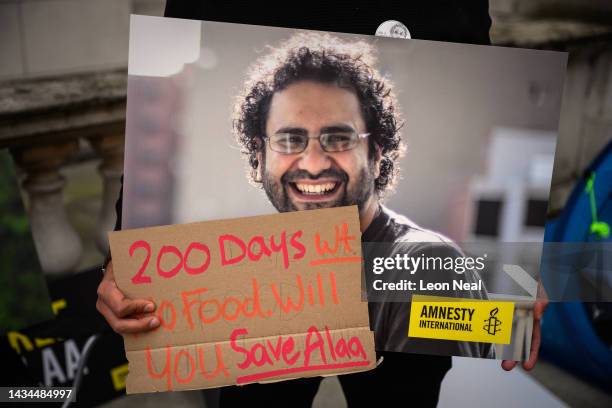 Man holds signs and placards as he stands with supporters during a protest calling for his release at the Foreign & Commonwealth Office on October...