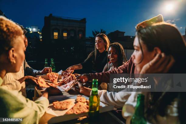 friends are dining together with pizza - rooftop dinner stock pictures, royalty-free photos & images
