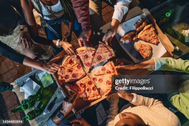 dinner party with friends - high angle view of people taking pizza slices - night delivery stock pictures, royalty-free photos & images