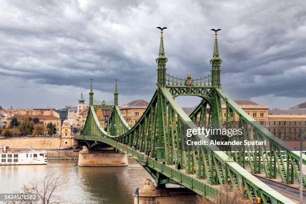 liberty bridge and the danube river on a cloudy day, budapest, hungary - budapest stock-fotos und bilder