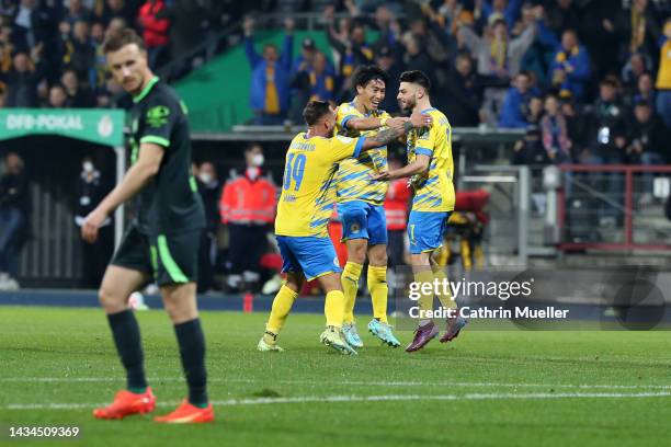 Maurice Multhaup of Eintracht Braunschweig celebrate with teammates Robin Krausse and Keita Endo after scoring their team's first goal during the DFB...