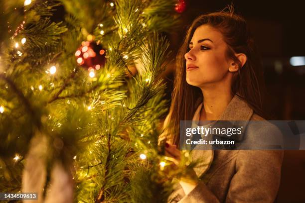 young woman next to a christmas tree outdoors - christmas tree close up stock pictures, royalty-free photos & images