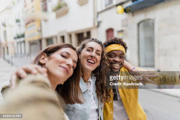 selfie photo of three friends laughing in the street - drei erwachsene stock-fotos und bilder