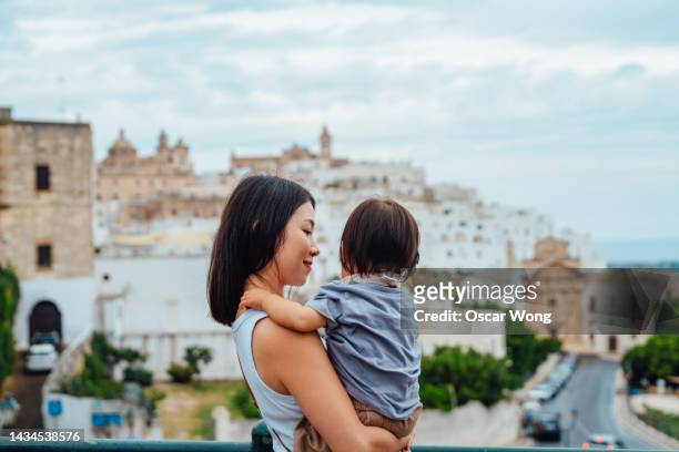 young asian mother travelling to ostuni, puglia, italy, with her toddler daughter. - puglia italy stock pictures, royalty-free photos & images