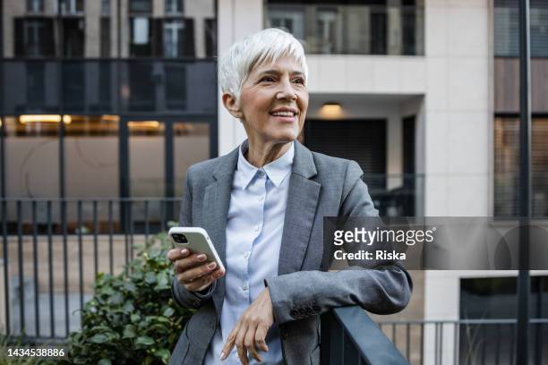 porträt einer hochrangigen geschäftsfrau mit smartphone - managing director stock-fotos und bilder