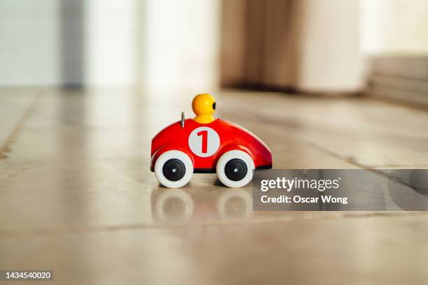 a retro-style red toy car on the floor - speelgoedauto stockfoto's en -beelden