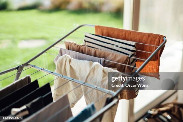 drying laundry on drying rack by the window with sunlight - folded clothes stock pictures, royalty-free photos & images