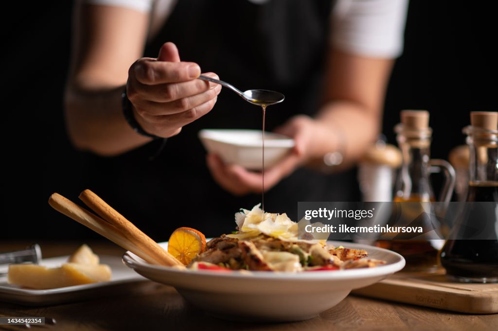 Eine Köchin gießt Soße auf Salat