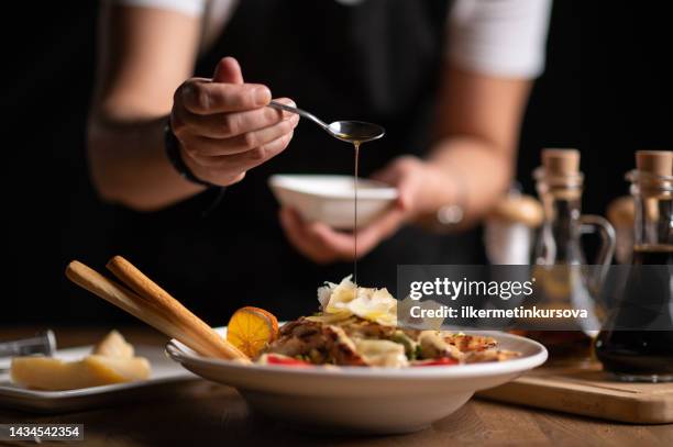 a female chef pouring sauce on salad - prato imagens e fotografias de stock