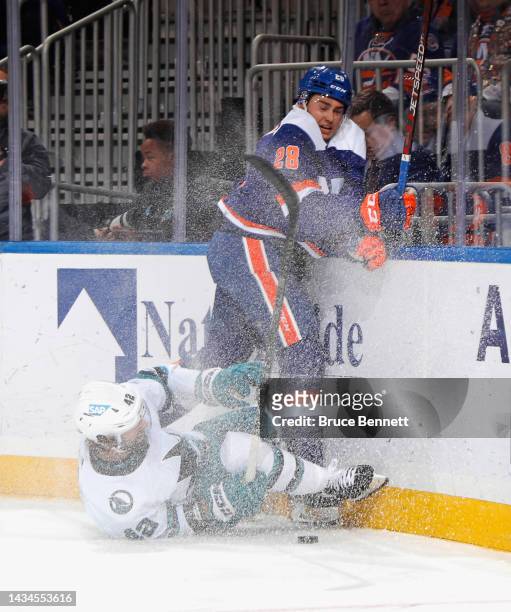 Alexander Romanov of the New York Islanders checks Jonah Gadjovich of the San Jose Sharks during the first period at UBS Arena on October 18, 2022 in...