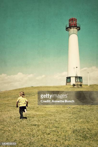 boy running towards lighthouse - annette haven imagens e fotografias de stock