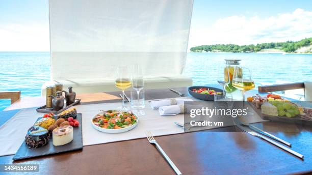 table with varied tasty snacks on yacht deck - dinner on the deck stock pictures, royalty-free photos & images
