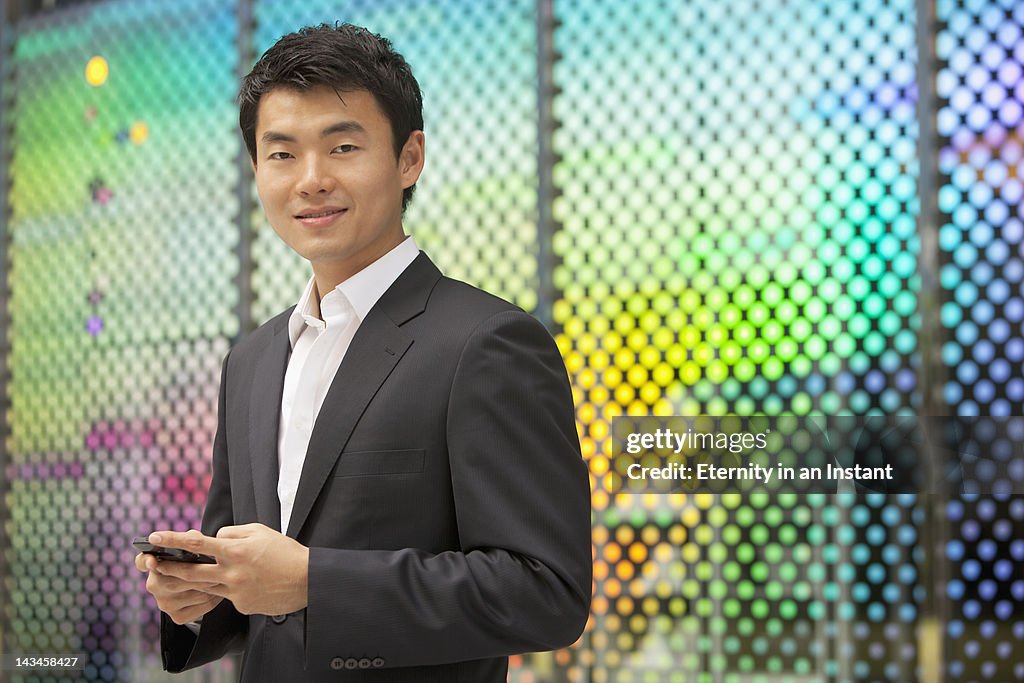 Asian Businessman smiling, holding smartphone