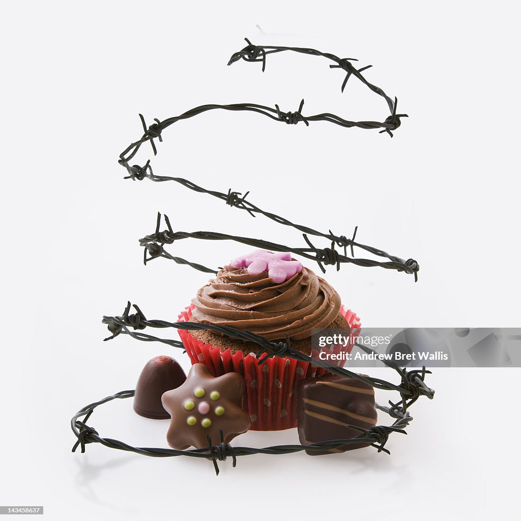 Barbed wire surrounds chocolate cake and candies