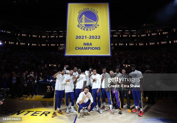 Golden State Warriors players pose with their Championship rings below the Championship banner during a ceremony prior to the game against the Los...