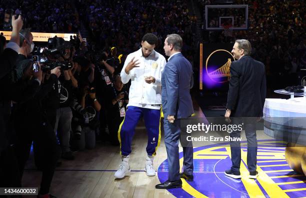 Stephen Curry of the Golden State Warriors receives his Championship ring from team owners Joe Lacob and Peter Guber during a ceremony prior to the...